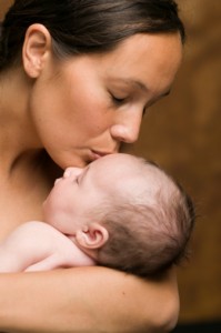 mother kissing newborn on head