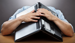 exhausted student with laptop over head on desk